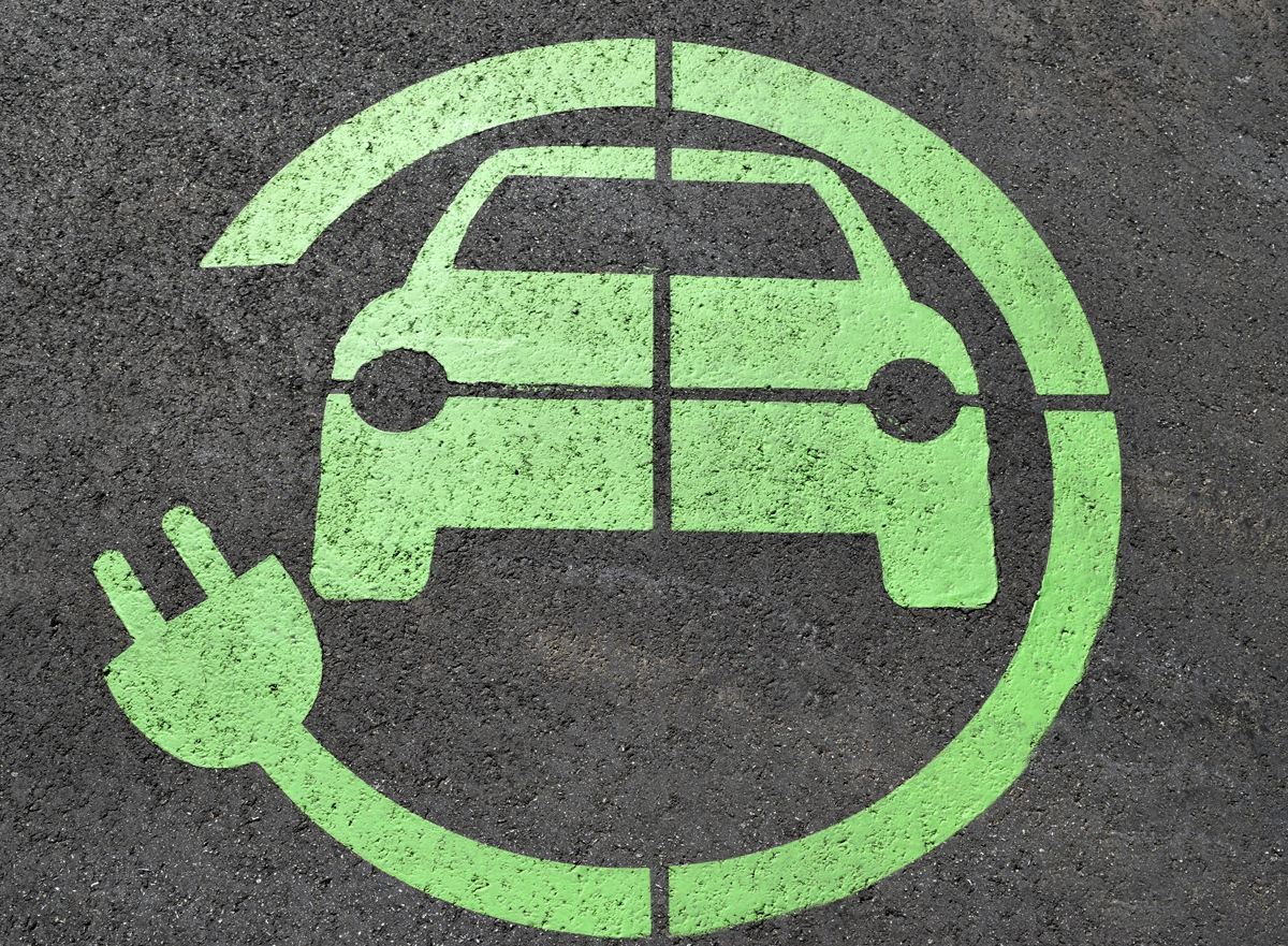 A green painted electric car sign in a parking space