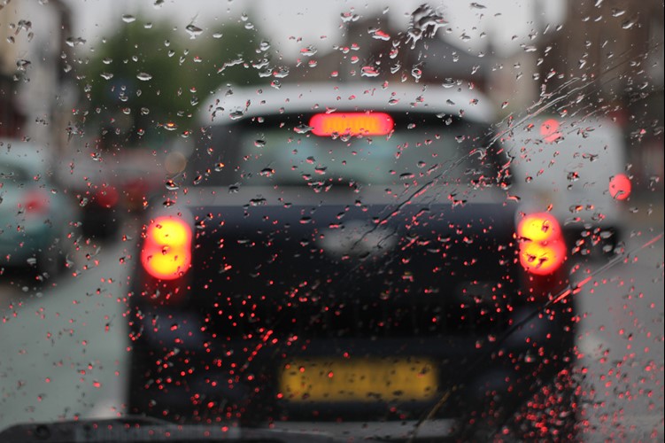 A wet windscreen with a car braking in-front